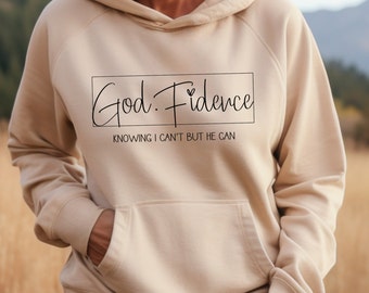 Może przedstawiać: Beżowa bluza z kapturem z czarnym nadrukiem, na którym widnieje napis "God. Fidence" i "Knowing I can't but He can".