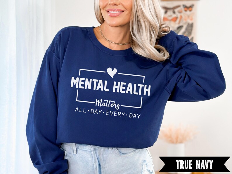 Peut inclure: Un sweat-shirt bleu marine avec le texte "MENTAL HEALTH Matters ALL DAY EVERY DAY" en blanc. Un c&oelig;ur blanc est au-dessus du mot "Matters". Les mots "TRUE NAVY" sont dans une banni&egrave;re noire en bas.