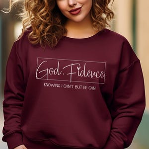以下が含まれることがあります： ワインレッドのトレーナーに、白い文字で「God. Fidence」と「Knowing I can't but He can.」と書かれています
