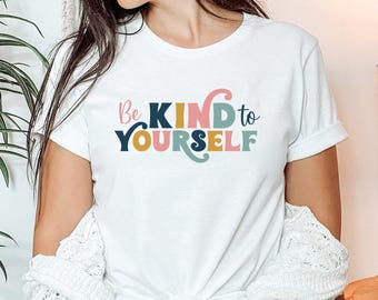 May include: White t-shirt with the text "Be KIND to YOURSELF" in colorful letters.