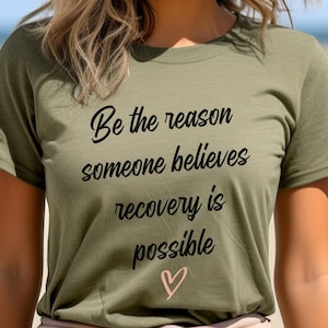 May include: A green t-shirt with the text "Be the reason someone believes recovery is possible" in black lettering and a pink heart.