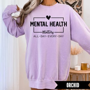 Peut inclure: Un sweat-shirt lilas avec l'inscription "MENTAL HEALTH Matters" en noir. Les mots "ALL DAY EVERY DAY" sont en dessous. Le sweat-shirt &agrave; manches longues est de couleur unie. Le mot "ORCHID" est affich&eacute; en bas de l'image.