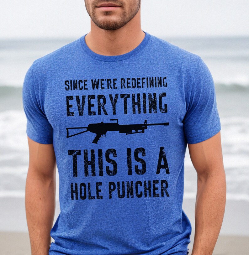 May include: A blue t-shirt with a distressed graphic of a rifle and the text "Since we're redefining everything, this is a hole puncher."