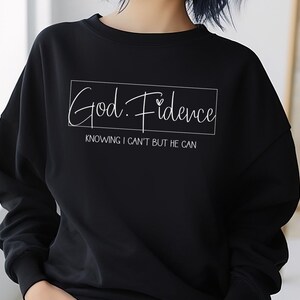 以下が含まれることがあります： 「God. Fidence」と「Knowing I can't but He can」という白い文字が書かれた黒いスウェットシャツ。