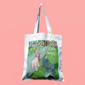 Könnte beinhalten: Weiße Tragetasche mit einer Illustration von zwei Zeichentrickhunden in einem Wald. Einer der Hunde trägt einen Cowboyhut und der andere ein blaues Bandana. Auf der Tasche steht "My Picnicking Pouch" und "LPS EXTRAORDINARY MAGIC."