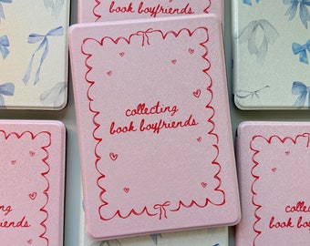 May include: A collection of pink and light blue book covers. The pink covers have a red scalloped border with the text "collecting book boyfriends" and small hearts. The light blue covers feature a bow pattern.