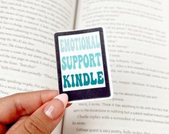 Puede incluir: Un marcapáginas azul turquesa y negro con el texto "Emotional Support Kindle" en letras blancas. El marcapáginas es una pegatina y está colocado en un libro.