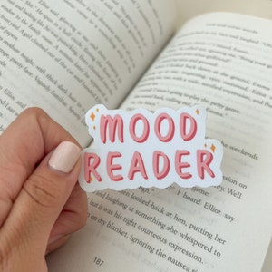 May include: A pink and white sticker with the words "MOOD READER" in a bold, pink font. The sticker is shaped like a speech bubble with stars around it.