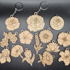 May include: A collection of wooden flower-shaped keychains. The keychains feature various floral designs, including roses, sunflowers, and lilies. Each keychain has a silver-colored metal ring attached for easy use. The wood has a natural, light brown color.