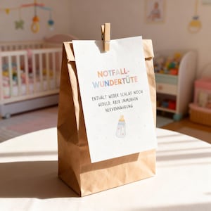 May include: A brown paper bag with a white card attached by a wooden clip. The card has text in pastel colors and a baby bottle illustration. The bag is on a white surface, with a crib and toys in the background.