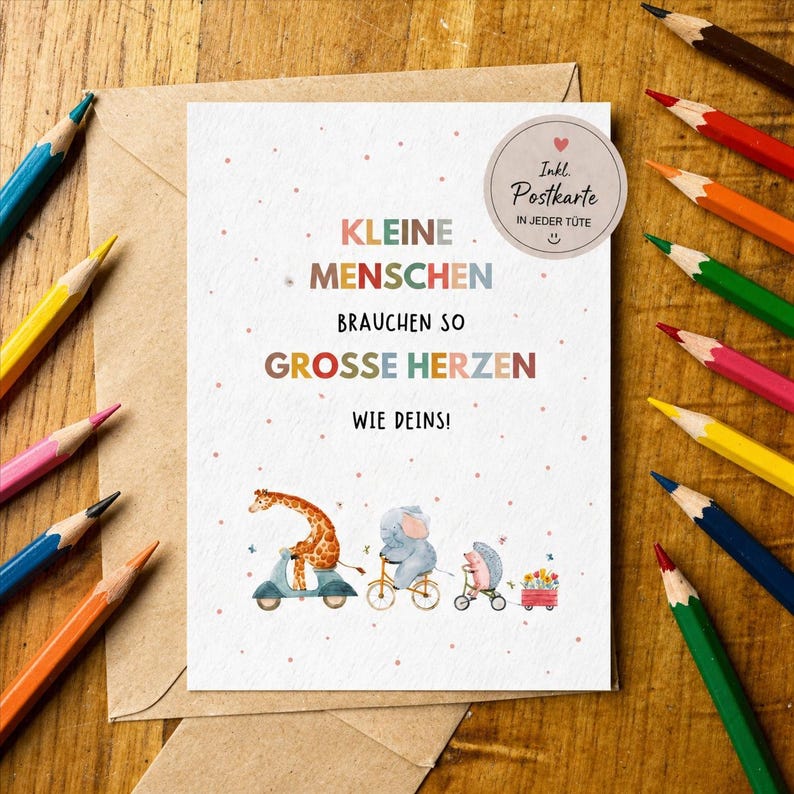 K&ouml;nnte beinhalten: Eine Gru&szlig;karte mit dem Text "KLEINE MENSCHEN BRAUCHEN SO GROSSE HERZEN WIE DEINS!" und Illustrationen einer Giraffe auf einem Roller, eines Elefanten auf einem Fahrrad und eines Igels in einem Wagen. Buntstifte umgeben die Karte.