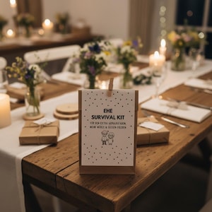 May include: A brown paper bag with a white card attached, reading "EHE SURVIVAL KIT" with text below. The bag is on a wooden table with other gifts and floral arrangements. The scene is lit by candles.