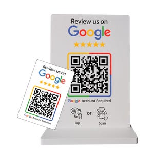 May include: A white sign and card with the text "Review us on Google" in blue, red, yellow, and green. Both feature a QR code and the Google logo. The sign has a base and the card is angled.