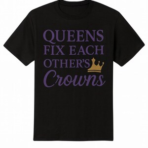 May include: Black t-shirt with the phrase "QUEENS FIX EACH OTHER'S Crowns" in purple text and a gold crown graphic. The shirt is a crew neck style.