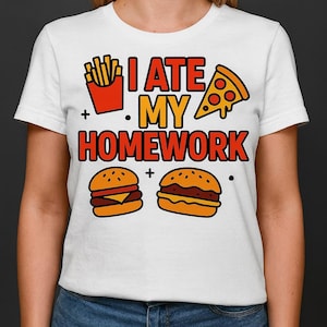 May include: White t-shirt with a colorful graphic design. The design includes a red container of fries, a pizza slice, two burgers, and the text "I ATE MY HOMEWORK" in orange and red.