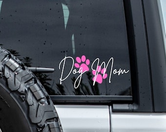 May include: A white car with a pink paw print and the text "Dog Mom" on the back window.