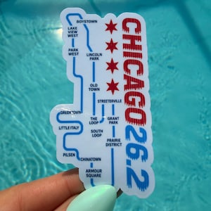 May include: A white die-cut sticker featuring a blue transit-style map of Chicago neighborhoods, four red six-pointed stars, and the red and blue text "CHICAGO 26.2". The map includes labels for Boystown, Lake View West, Park West, Lincoln Park, Old Town, Streeterville, The Loop, Grant Park, South Loop, Prairie District, Greektown, Little Italy, Pilsen, Chinatown, and Armour Square.