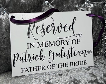 Könnte beinhalten: Weißes Schild mit lila Band, mit der Aufschrift "Reserviert im Gedenken an Patrick Godesteanu Vater der Braut"
