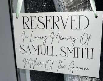Könnte beinhalten: Ein weißes Schild mit schwarzem Text, auf dem steht "RESERVED In Loving Memory Of SAMUEL SMITH Mother Of The Groom". Das Schild hängt an einem hellgrünen Band.