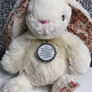 May include: White plush bunny with pink nose and floral fabric ears. A silver charm with a white background and black text reads "Willow Today our flower girl, but one day you will hold the bouquet. Here is something of for your wedding day. 20/01/2019"