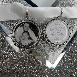 May include: Two silver charm pendants with a white ribbon. One pendant has a black and white photo of a father and daughter. The other pendant has the text "Dad Walk With Me Today & Always" in black script.