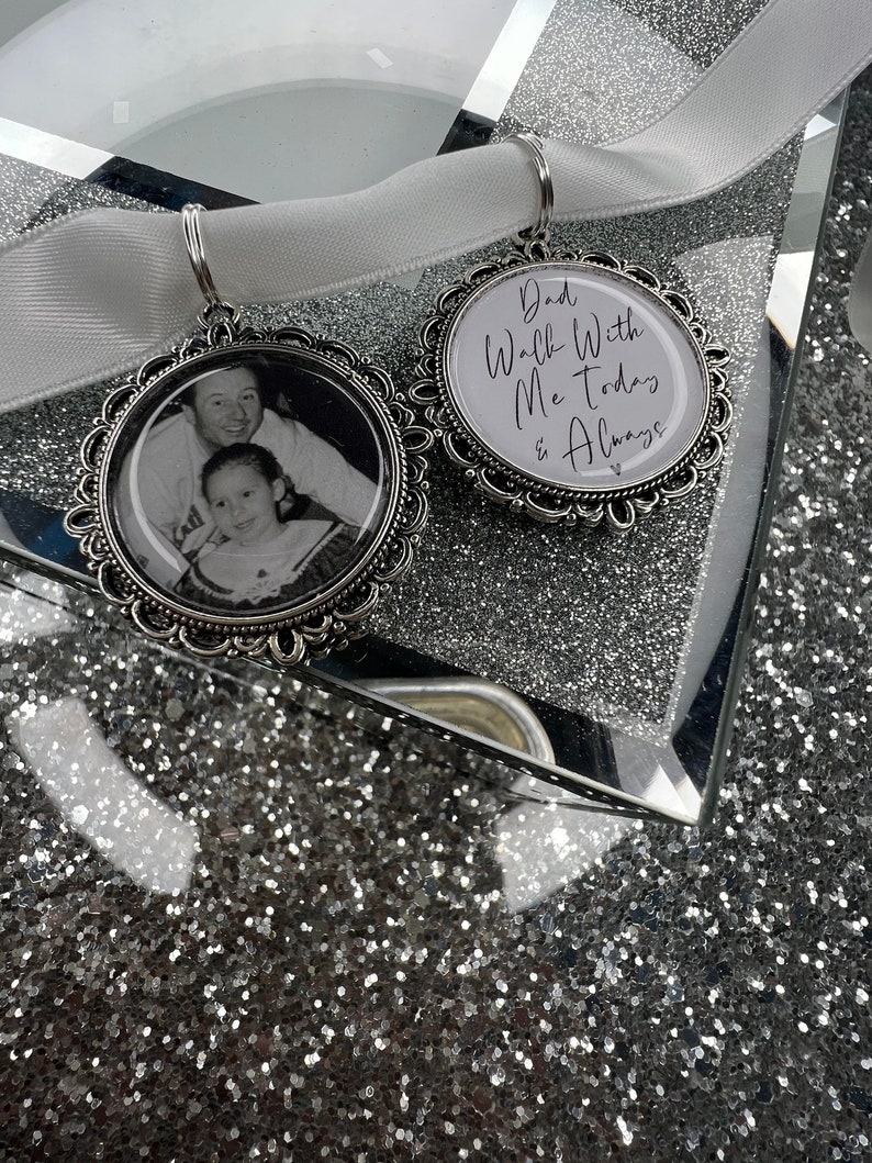 May include: Two silver charm pendants with a white satin ribbon. One pendant features a photo of a father and daughter, and the other pendant has the text "Dad Walk With Me Today & Always".