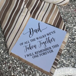 May include: A blue card with the text "Dad, of all the walks we've taken together, I will remember this one forever." The card is on top of a brown and white striped tie.