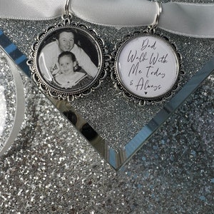 May include: Two silver charms with a white satin ribbon. One charm has a black and white photo of a father and daughter. The other charm has the text "Dad Walk With Me Today & Always".