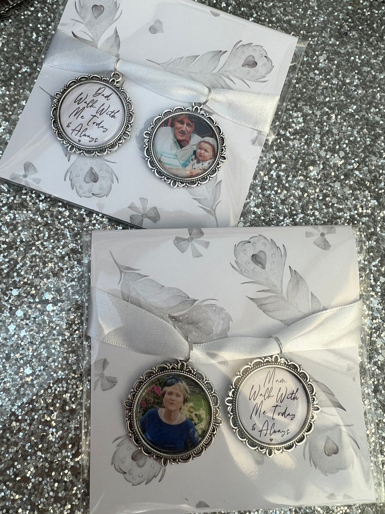 May include: Two silver-toned photo charms with white ribbon. The charms feature a photo of a woman and child, and the text "Dad Walk With Me Today & Always" and "Mom Walk With Me Today & Always".
