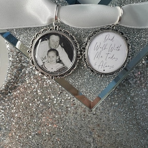 May include: Two silver charm pendants with a white satin ribbon. One pendant features a black and white photo of a father and daughter. The other pendant has the text "Dad Walk With Me Today & Always" in white script.