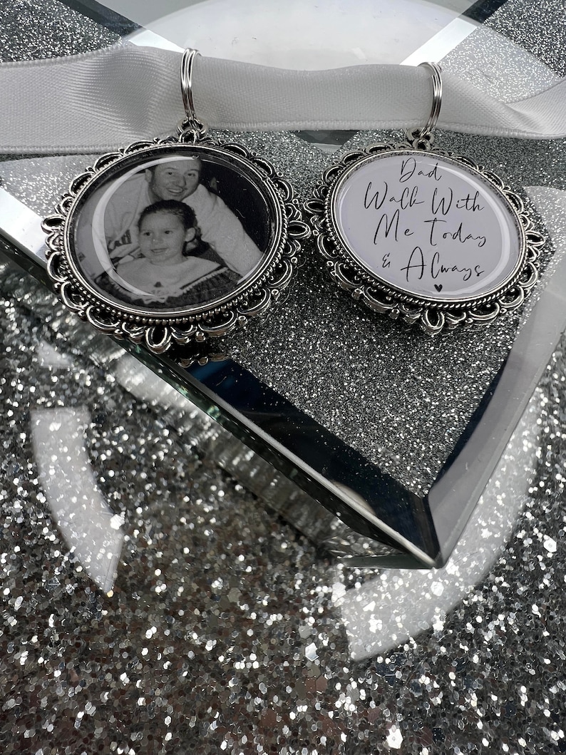 May include: Two silver charm ornaments. One features a black and white photo of a father and daughter. The other has the text "Dad Walk With Me Today & Always" with a small heart.