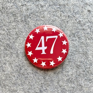 May include: Red button with a white circle of stars around the number 47 in white.