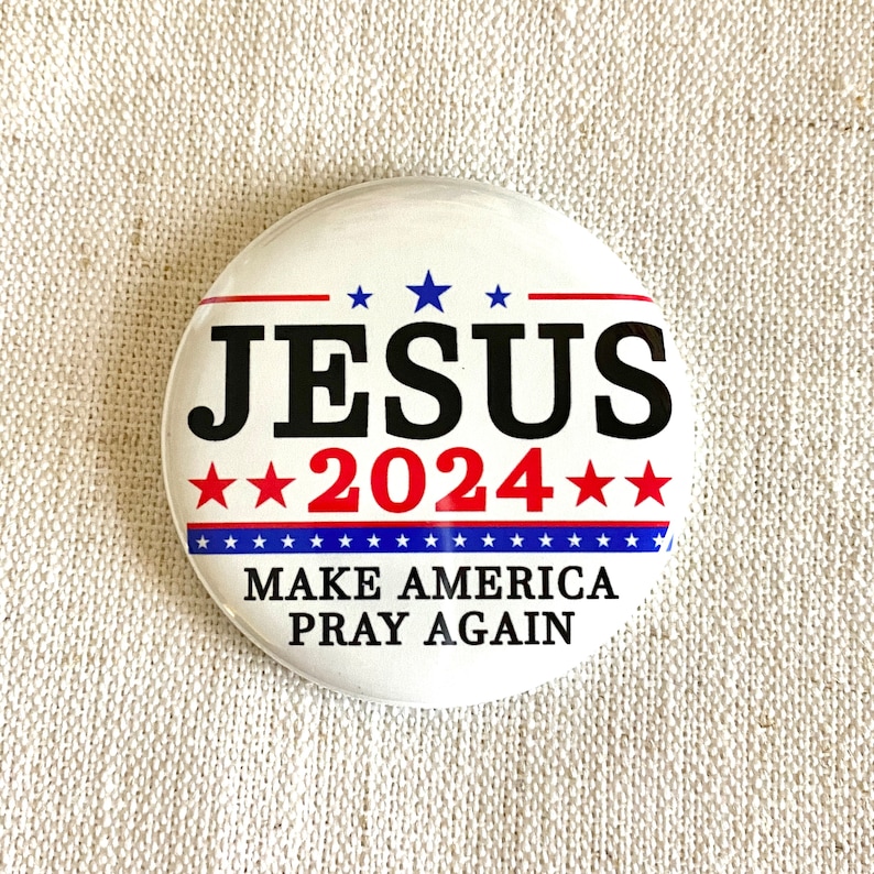 Puede incluir: Un bot&oacute;n blanco con estrellas y rayas rojas, azules y blancas. El bot&oacute;n dice "JESUS 2024" y "MAKE AMERICA PRAY AGAIN".