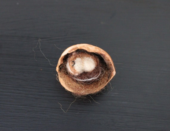Tiny felted chipmunk sleeping in a walnut shell