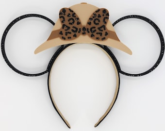 Könnte beinhalten: Schwarzes Stirnband mit zwei schwarzen glitzernden Ohren und einem braunen und schwarzen Hut mit Leopardenmuster und einer Schleife oben.