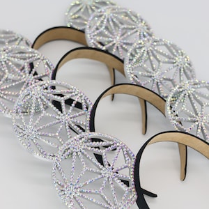 May include: Set of five silver headband with a geometric design. Each headband features a large, round, silver, sparkly, geometric design.