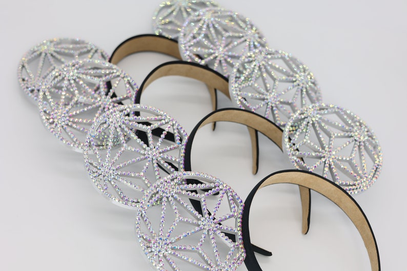 May include: Set of five silver headband with a geometric design. Each headband features a large, round, silver, sparkly, geometric design.