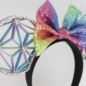 May include: Rainbow sequined bow headband with iridescent geometric ears. The ears are decorated with rhinestones.
