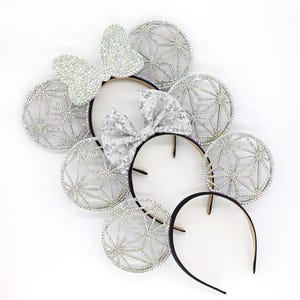 May include: Silver sparkly headband with a bow and three pairs of sparkly ears. Each ear is a geometric design.