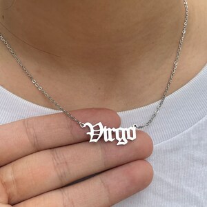May include: Silver necklace with a silver pendant that says "Virgo" in a gothic font.