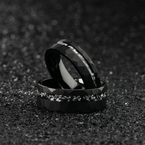 K&ouml;nnte beinhalten: Zwei schwarze Ringe aus Wolframcarbid mit einer silbernen Einlage. Die Ringe sind &uuml;bereinander gestapelt.