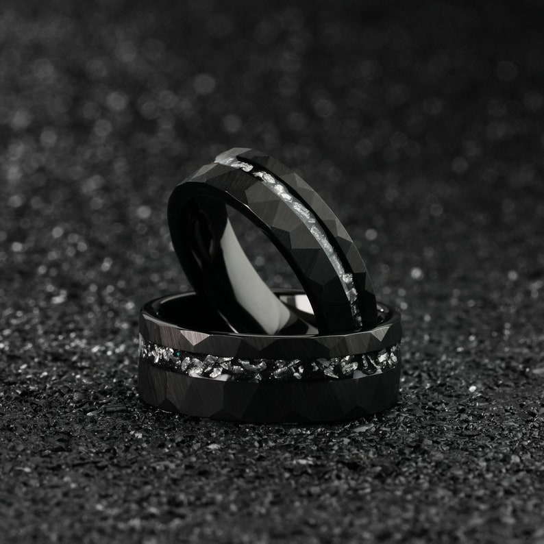 K&ouml;nnte beinhalten: Zwei schwarze Ringe aus Wolframcarbid mit einer silbernen Einlage. Die Ringe sind &uuml;bereinander gestapelt.