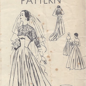 Puede incluir: Un patrón vintage de Vogue Couturier para un vestido de novia. El patrón muestra a una novia con un vestido largo y fluido con un bolero de encaje y un velo. También se muestran dos damas de honor con vestidos sencillos y elegantes.