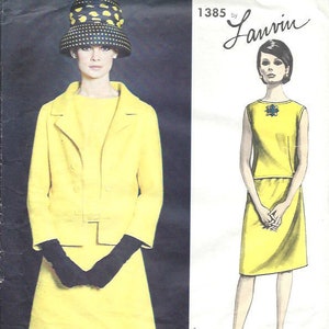 Könnte beinhalten: Vintage Vogue Paris Original Schnittmuster Nummer 1385 von Lanvin für ein gelbes Kleid und Jacken-Set. Das Model trägt einen schwarz-weißen Polka-Dot-Hut.