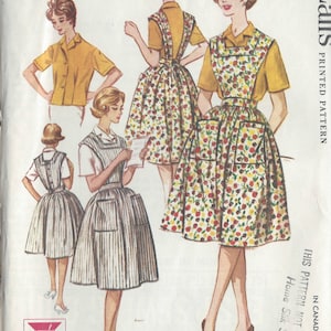 Pode incluir: Padrão de costura vintage para um avental e uma camisa para mulher. O padrão é da McCall's e é impresso em papel. O padrão é para o tamanho 14.5 e é de 1960. O padrão mostra uma mulher vestindo uma camisa amarela e um avental com estampa floral. O padrão também mostra uma mulher vestindo uma camisa branca e um avental listrado.