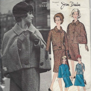 May include: A vintage sewing pattern for a woman's suit designed by Jean Dessès. The pattern is Vogue Paris Original pattern number 1122. The pattern shows a woman wearing a grey suit with a cape and a matching hat. The pattern also shows a woman wearing a brown and white tweed suit and a woman wearing a blue suit.