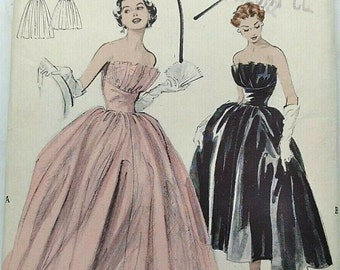 May include: Vintage sewing pattern for a strapless evening gown. The pattern is for a size 14, bust 32. The pattern includes two different styles of gowns, one in pink and one in black.