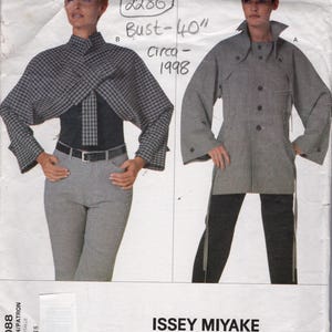 May include: Vogue pattern 2286 featuring two Issey Miyake designs. One design is a wrap top with a plaid pattern, and the other is a long grey coat. The bust measurement is 101.6 cm. Circa 1998. The Vintage Pattern Shop.