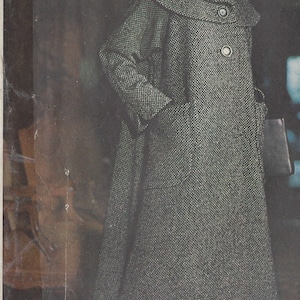 May include: A black and white patterned coat with a large collar and a red hat. The text "designed exclusively for McCall's by TRIGÈRE" is printed on the image.
