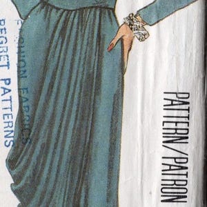 May include: A teal blue dress with a V-neckline, long sleeves, and a gathered skirt. The dress has a belt at the waist and is shown on a model with short brown hair. The text "PATTERN/PATRON" is printed on the white background.
